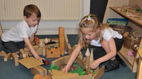 Children playing with small world toys in EYFS. 